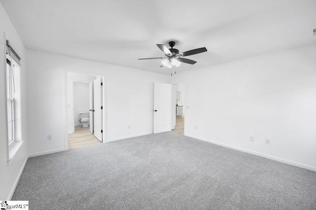 unfurnished bedroom with ceiling fan, light colored carpet, and connected bathroom