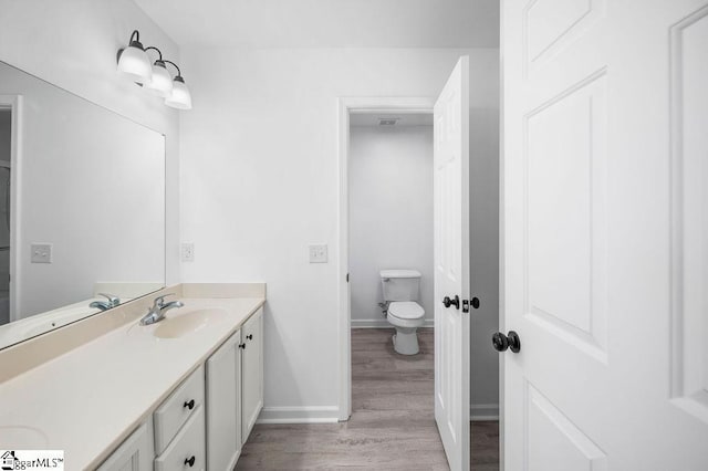 bathroom with toilet, wood-type flooring, and vanity