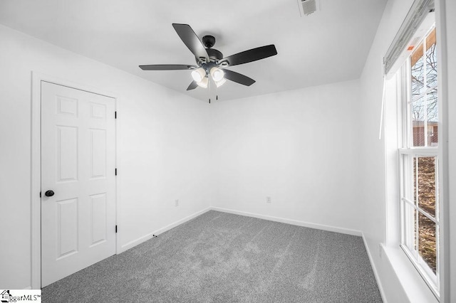 carpeted empty room with ceiling fan and plenty of natural light