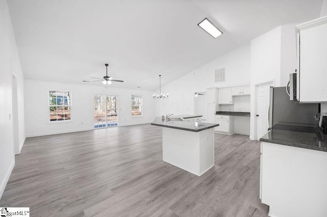 kitchen with hanging light fixtures, an island with sink, white cabinets, light hardwood / wood-style flooring, and ceiling fan with notable chandelier