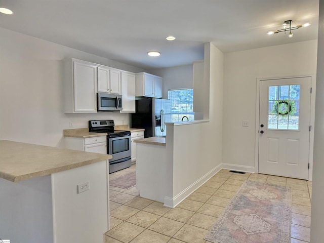 kitchen featuring stainless steel appliances, white cabinets, light tile patterned floors, and kitchen peninsula