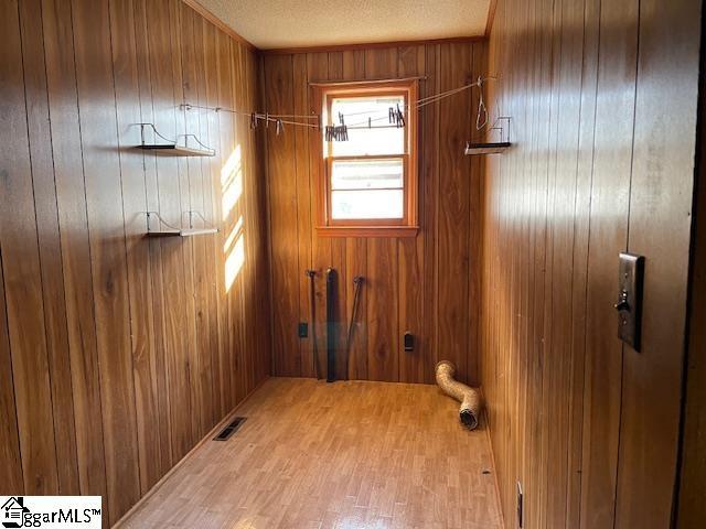 washroom featuring wood walls, visible vents, and a textured ceiling