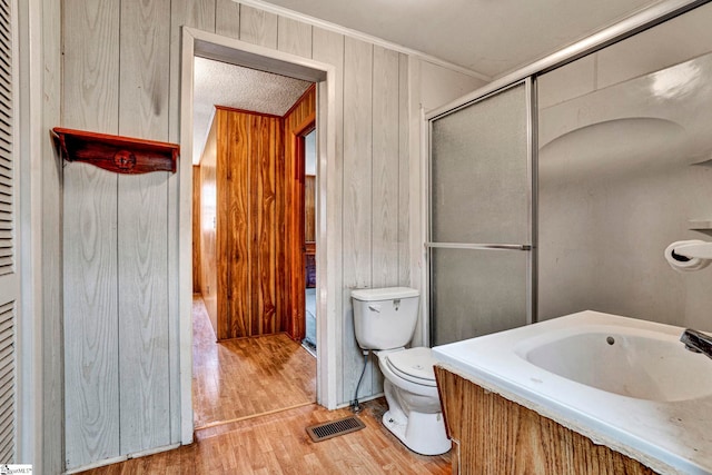 full bath featuring visible vents, toilet, a shower with shower door, a sink, and wood finished floors