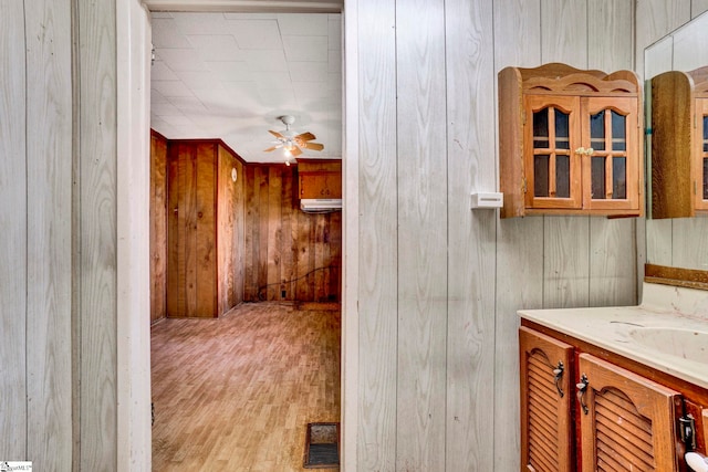 bathroom featuring wooden walls, wood finished floors, visible vents, vanity, and a ceiling fan