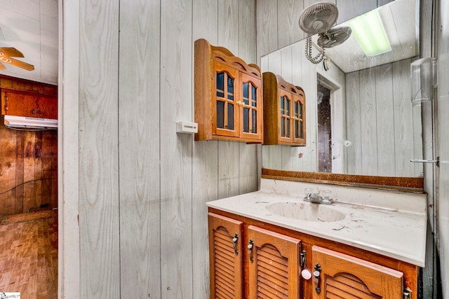 bathroom with vanity, a ceiling fan, and wooden walls