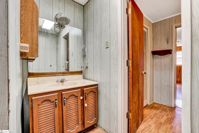 bathroom with wood walls, crown molding, wood finished floors, and vanity