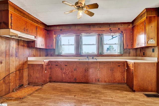 kitchen with light wood-style floors, plenty of natural light, brown cabinets, and under cabinet range hood