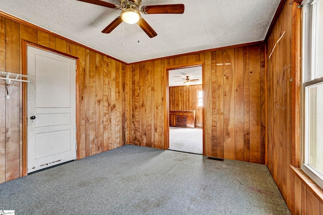 carpeted empty room featuring wooden walls and a textured ceiling