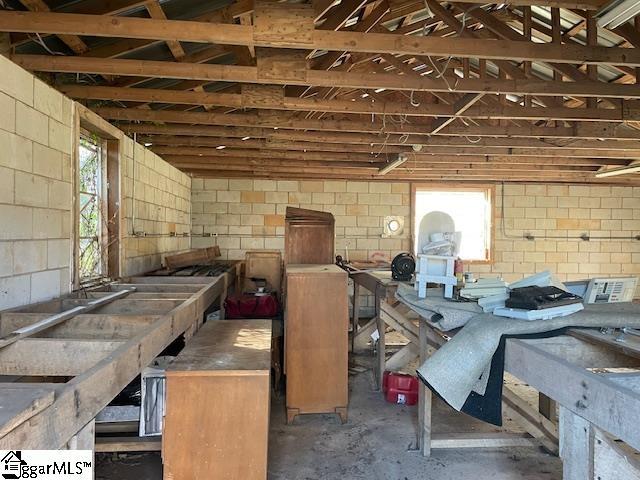 miscellaneous room featuring concrete block wall and unfinished concrete floors