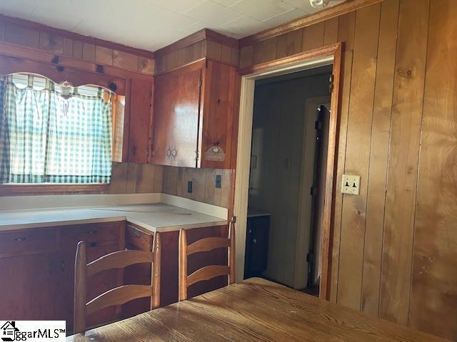 kitchen featuring brown cabinets, light countertops, and wooden walls