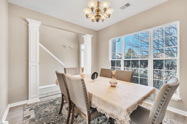 dining space with an inviting chandelier, decorative columns, plenty of natural light, and wood-type flooring