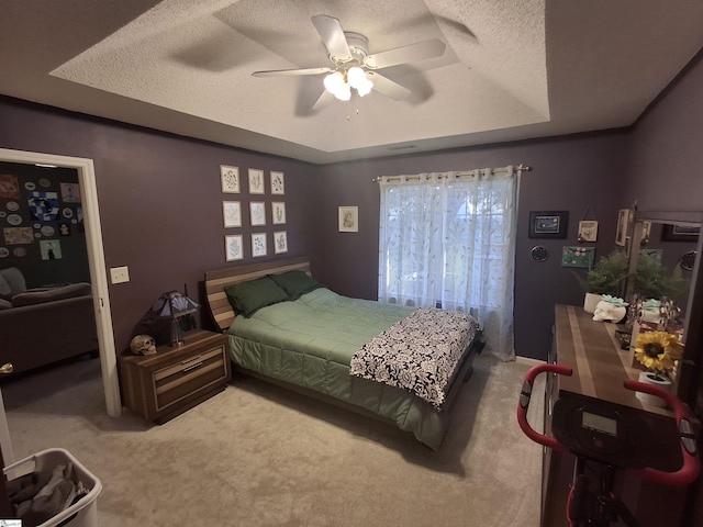 bedroom with ceiling fan, carpet flooring, a textured ceiling, and a tray ceiling