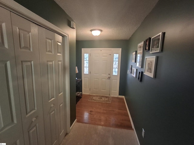 doorway to outside with dark wood-type flooring and a textured ceiling