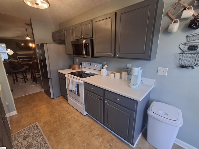 kitchen featuring stainless steel appliances, a textured ceiling, ceiling fan, and gray cabinetry