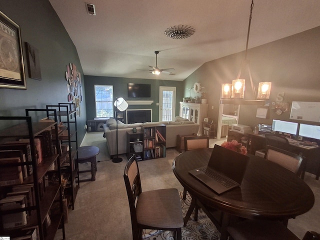 carpeted dining area featuring lofted ceiling and ceiling fan with notable chandelier