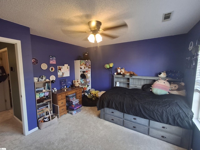 bedroom with ceiling fan, carpet, and a textured ceiling