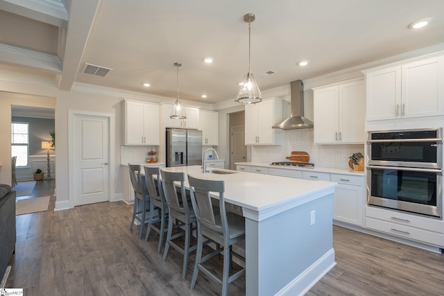 kitchen featuring appliances with stainless steel finishes, sink, white cabinetry, and wall chimney range hood