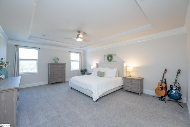 carpeted bedroom with ceiling fan, ornamental molding, and a tray ceiling