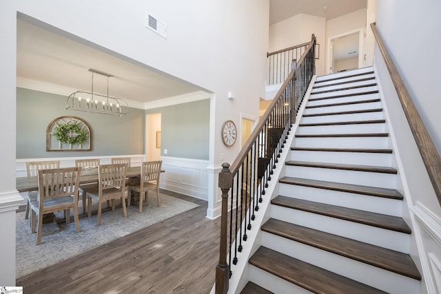 unfurnished dining area with dark hardwood / wood-style flooring, crown molding, and a chandelier