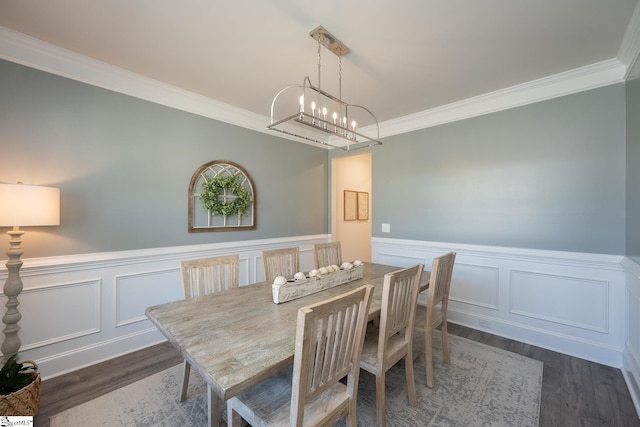 dining space with dark wood-type flooring, an inviting chandelier, and ornamental molding