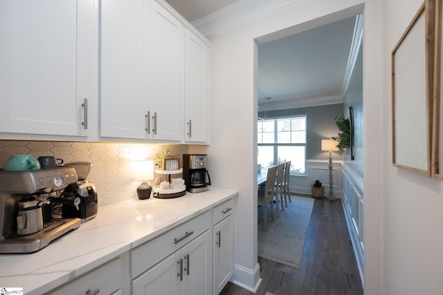 kitchen featuring dark hardwood / wood-style flooring, crown molding, white cabinets, and light stone counters