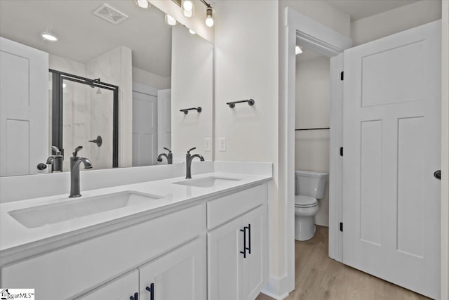 bathroom featuring toilet, wood-type flooring, walk in shower, and vanity