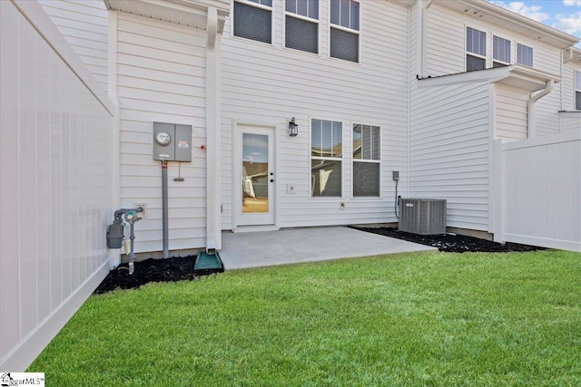 rear view of property featuring a lawn, central AC, and a patio area