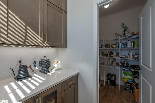 interior space with backsplash, dark hardwood / wood-style floors, and light stone counters