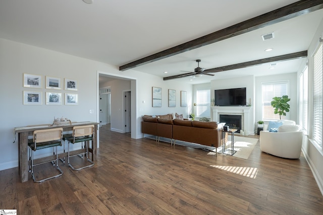 living room with ceiling fan, dark wood-type flooring, and beamed ceiling