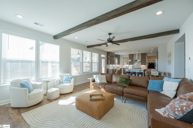 living room featuring light wood-type flooring, ceiling fan, and beam ceiling