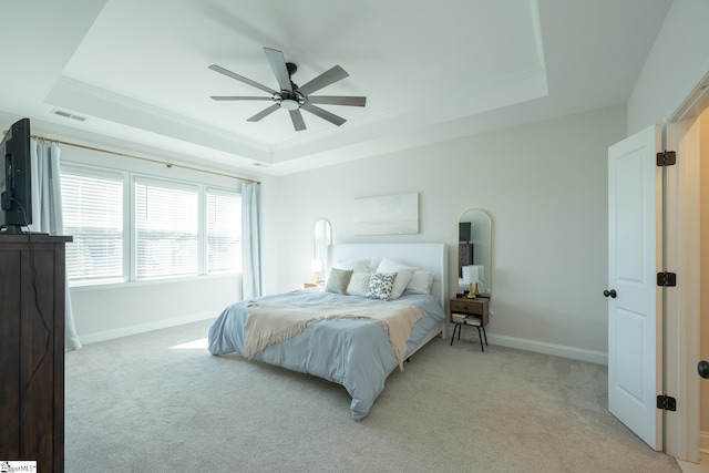 carpeted bedroom featuring a raised ceiling, ceiling fan, and ornamental molding