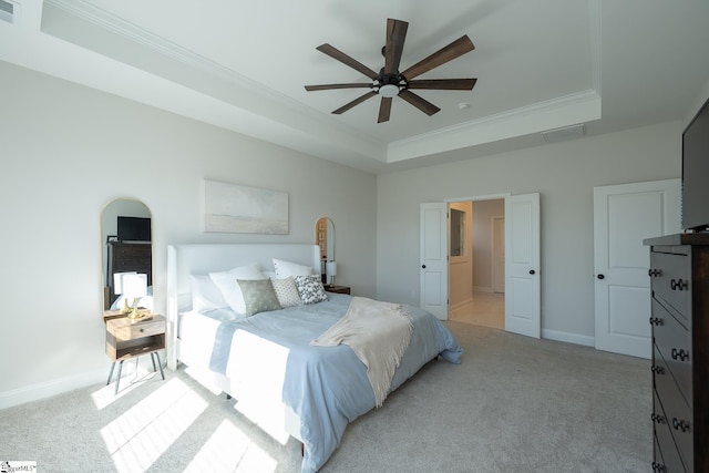 carpeted bedroom with ceiling fan, a tray ceiling, and ornamental molding