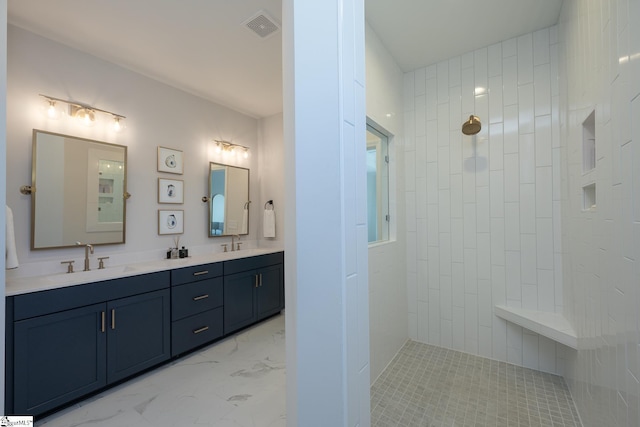 bathroom with tiled shower and vanity