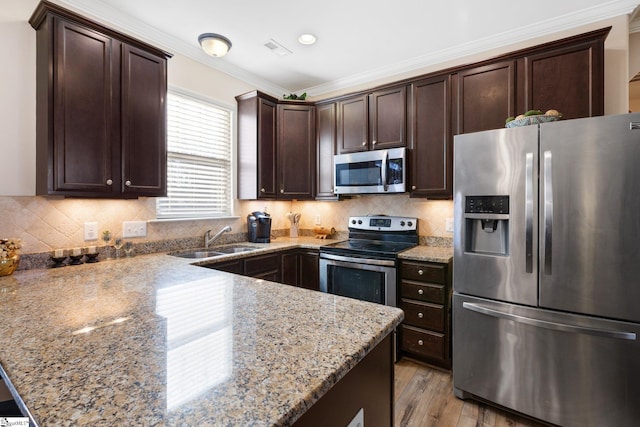 kitchen with sink, crown molding, light stone countertops, stainless steel appliances, and dark brown cabinets