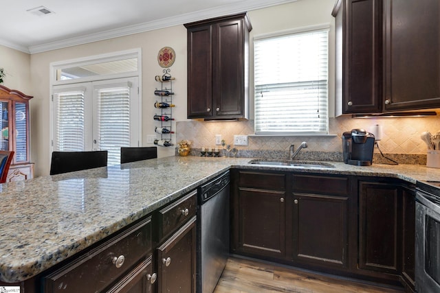 kitchen with kitchen peninsula, dishwasher, light hardwood / wood-style flooring, light stone counters, and sink