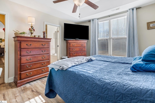 bedroom featuring ceiling fan, ensuite bath, and light wood-type flooring