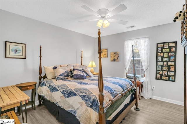 bedroom with a textured ceiling, ceiling fan, and hardwood / wood-style flooring