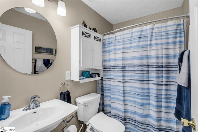 bathroom featuring a textured ceiling, toilet, walk in shower, and sink