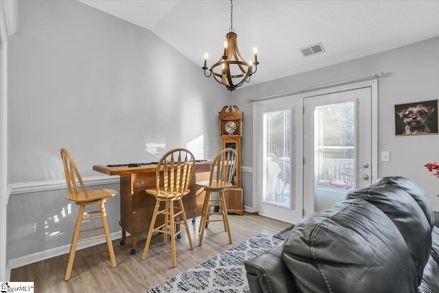 dining area featuring indoor bar, lofted ceiling, a chandelier, and light wood-type flooring