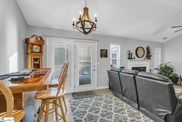 dining room featuring ceiling fan with notable chandelier, a textured ceiling, and light hardwood / wood-style flooring