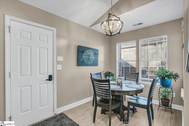 dining area with lofted ceiling, light wood-type flooring, and a chandelier