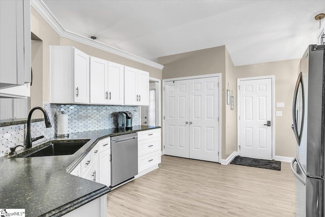 kitchen featuring white cabinetry, stainless steel appliances, backsplash, light wood-type flooring, and sink