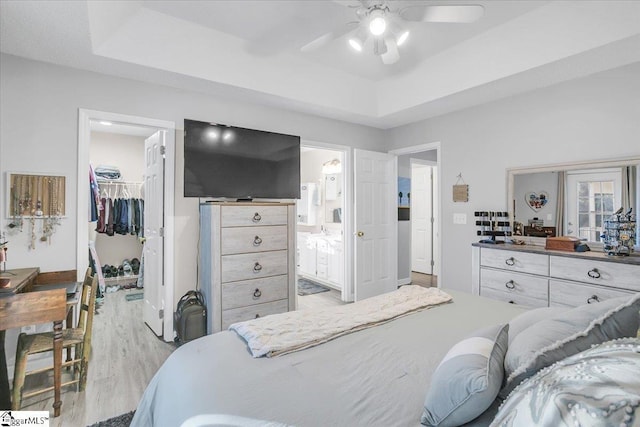 bedroom featuring ensuite bathroom, a closet, a walk in closet, and a tray ceiling