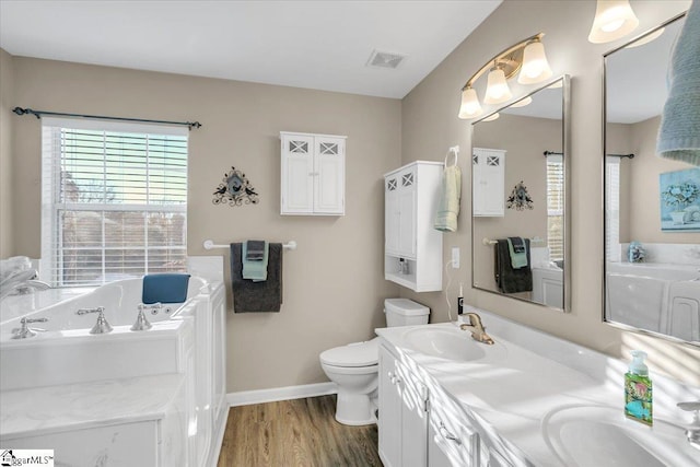 bathroom featuring hardwood / wood-style floors, toilet, a bath, and vanity