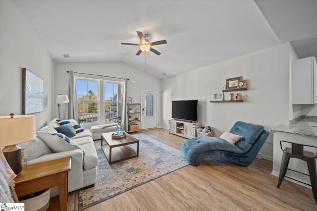 living room featuring ceiling fan, light hardwood / wood-style flooring, and lofted ceiling