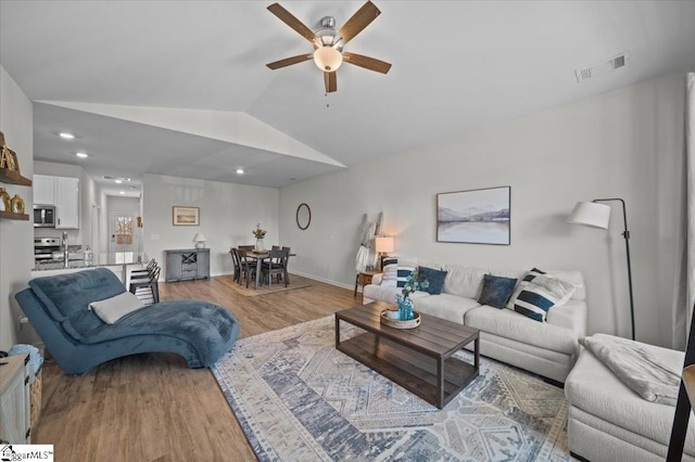 living room with ceiling fan, lofted ceiling, light hardwood / wood-style flooring, and sink