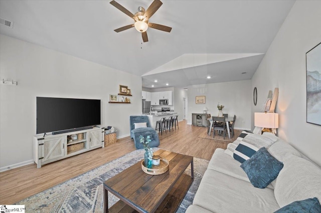 living room featuring ceiling fan, vaulted ceiling, and light hardwood / wood-style floors