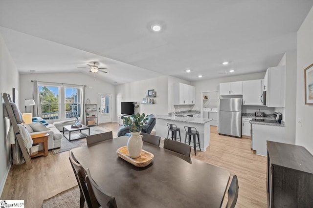 dining space featuring ceiling fan, lofted ceiling, light hardwood / wood-style floors, and sink