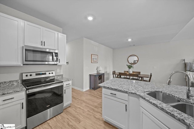 kitchen featuring light stone countertops, sink, white cabinets, and appliances with stainless steel finishes