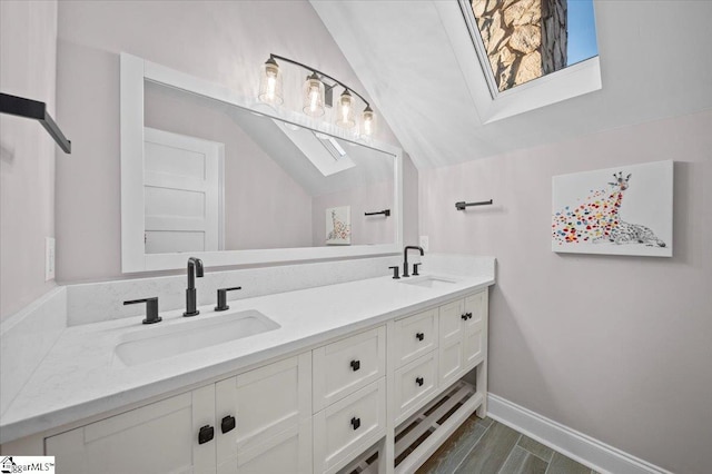 bathroom featuring vaulted ceiling with skylight and vanity